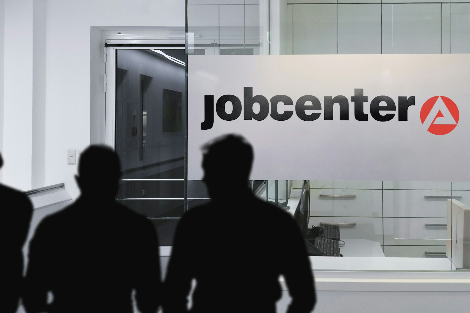 Menschen stehen vor einem Jobcenter.