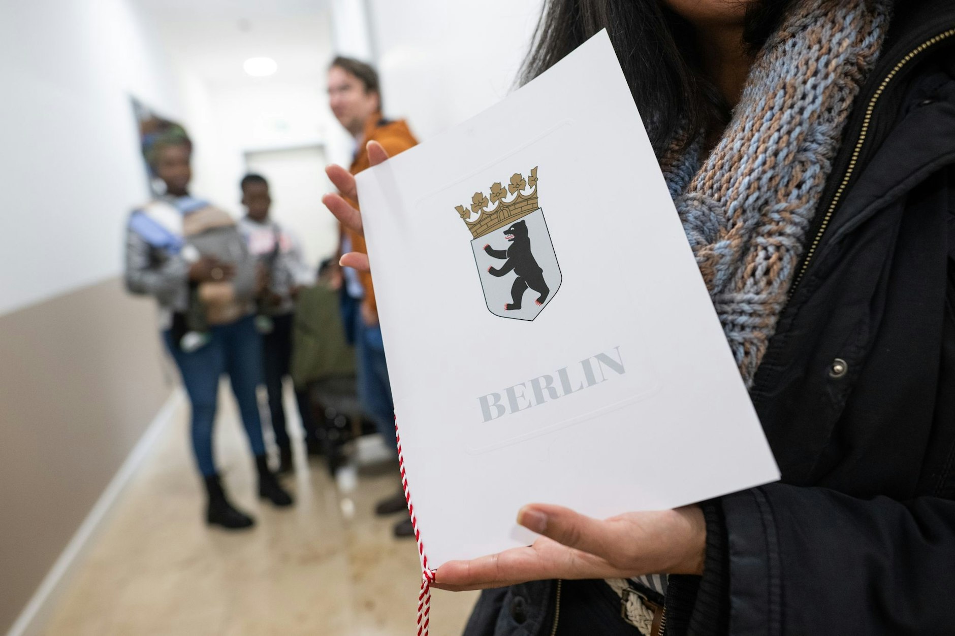 Eine Frau zeigt im Landesamt für Einwanderung ihre Einbürgerungsurkunde mit dem Wappen Berlins.