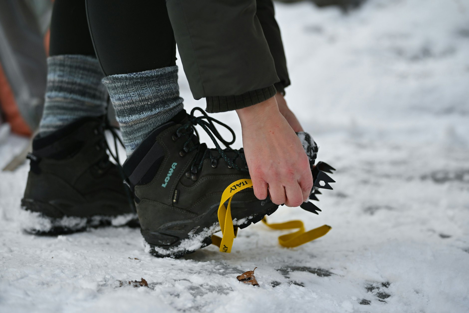 Eine Frau befestigt Spikes an ihren Schuhen – in Berlin sind die rutschfesten Aufsätze derzeit kaum noch erhältlich.