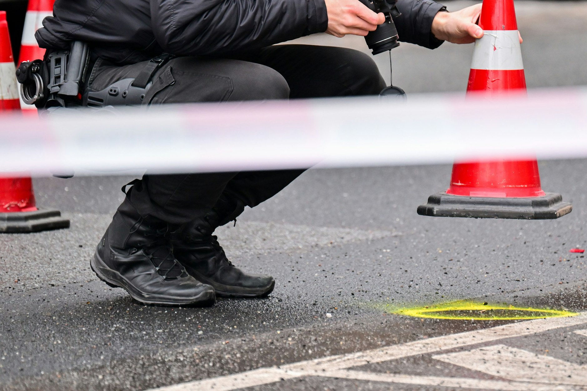 Ein Polizeibeamter fotografiert vor einer Shishabar in Wedding ein Beweismittel auf der Straße.