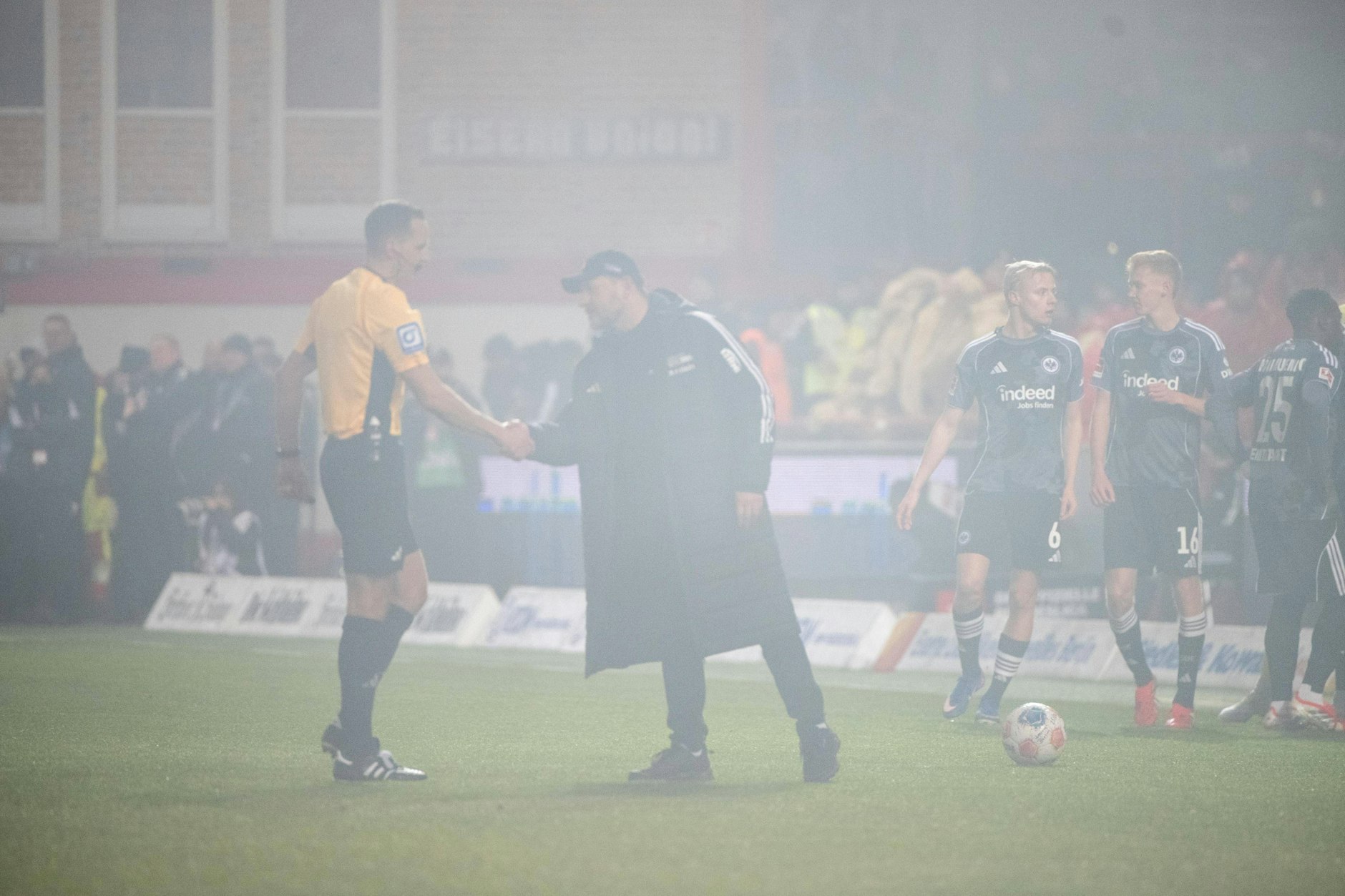 Trainer Steffen Baumgart begrüßt gegen Frankfurt während der Unterbrechnung wegen des Feuerwerks Schiedsrichter  Sören Storks.