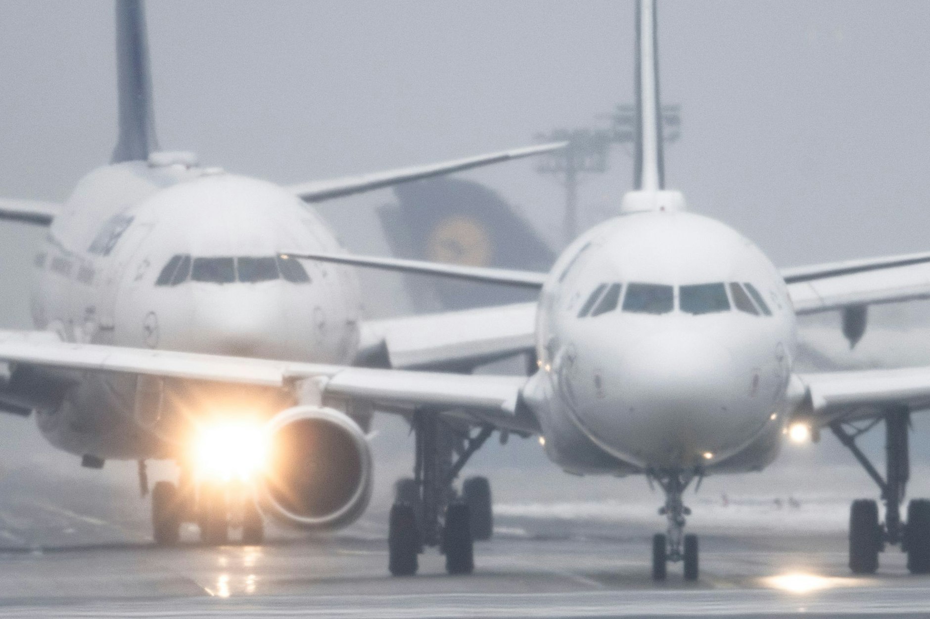 Passagiermaschinen warten bei Sprühregen und Schnee auf dem Flughafen Frankfurt auf ihre Startfreigabe.