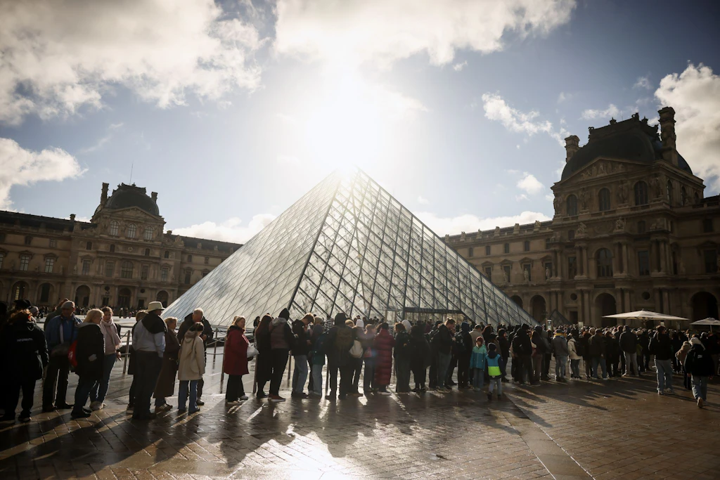 Besucher stehen vor der Glaspyramide im Louvre in einer Schlange.