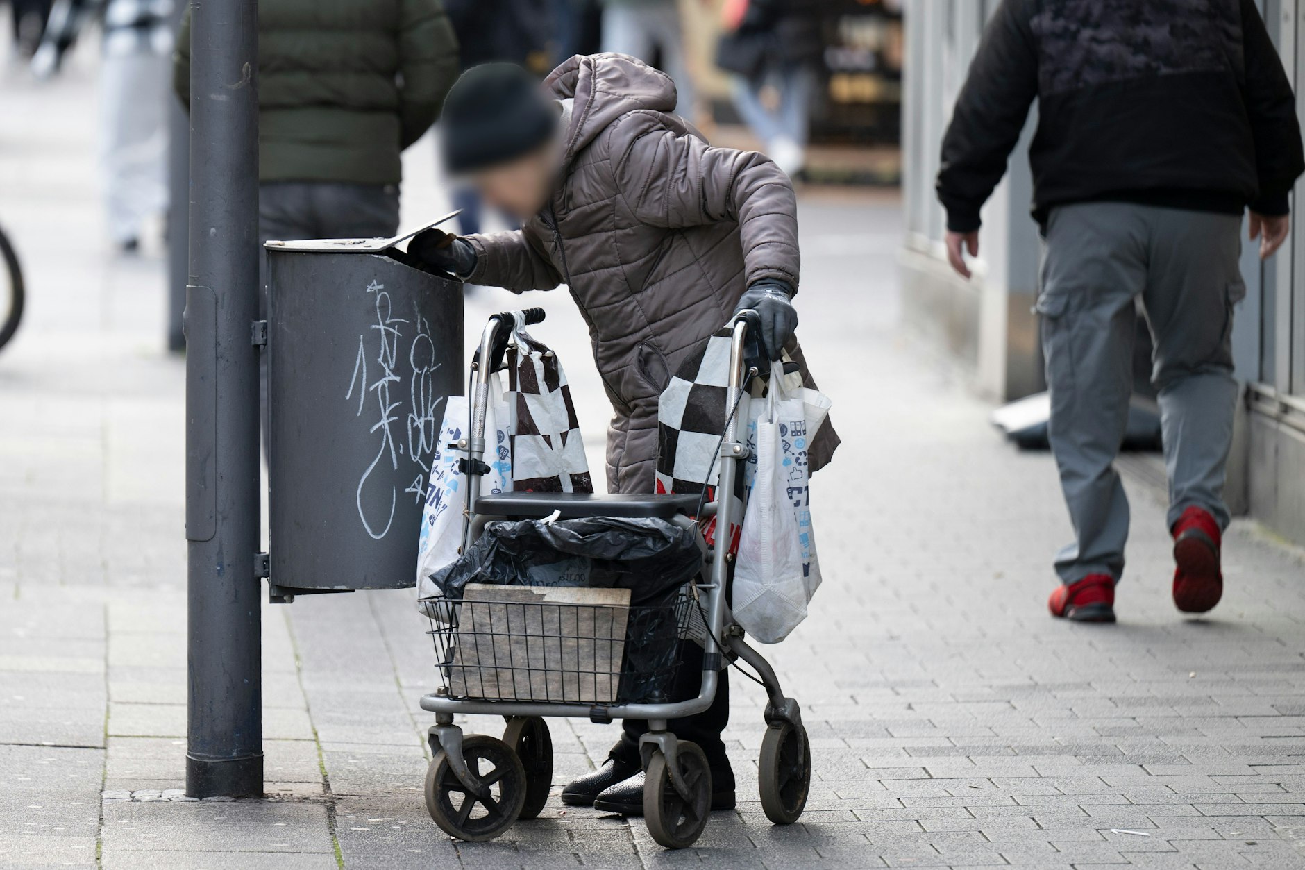 Eine alte Frau sucht in Mülleimern in der Innenstadt von Offenbach nach Pfandflaschen.