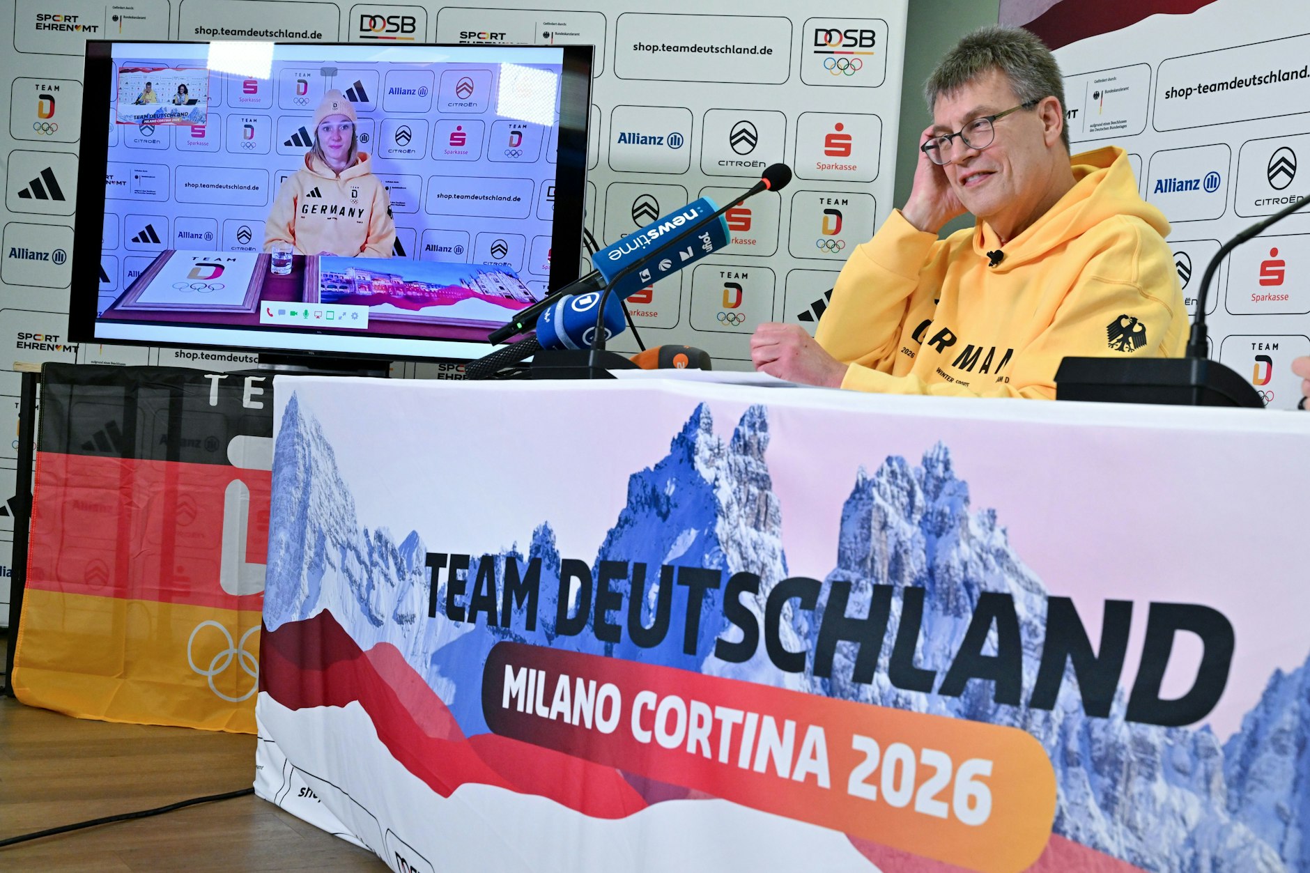 DOSB-Präsident Thomas Weikert (M) spricht mit Skispringerin Katharina Schmid (l), die zugeschaltet ist.