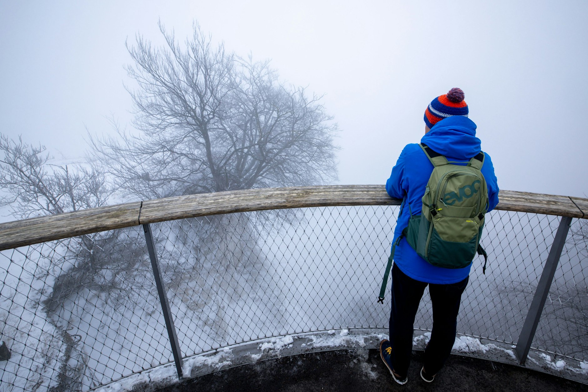 Im dichten Nebel steht ein Besucher auf dem Skywalk über dem Königsstuhl an den Kreidefelsen der Ostseeinsel Rügen.
