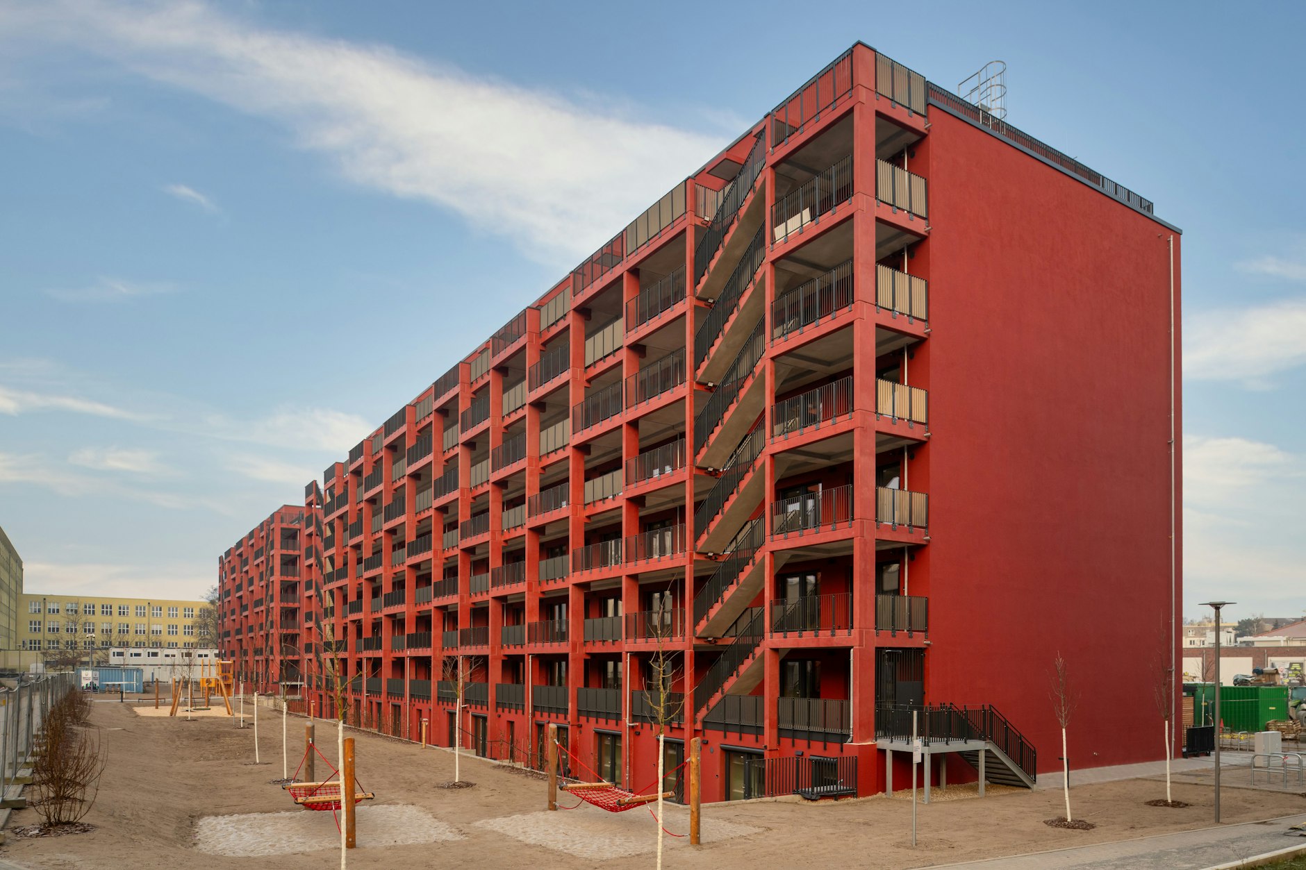 Die neuen Gebäude im Havelufer-Quartier: Es gibt eine Außentreppe, ringsherum sind Spielplätze und Hängematten zu sehen.