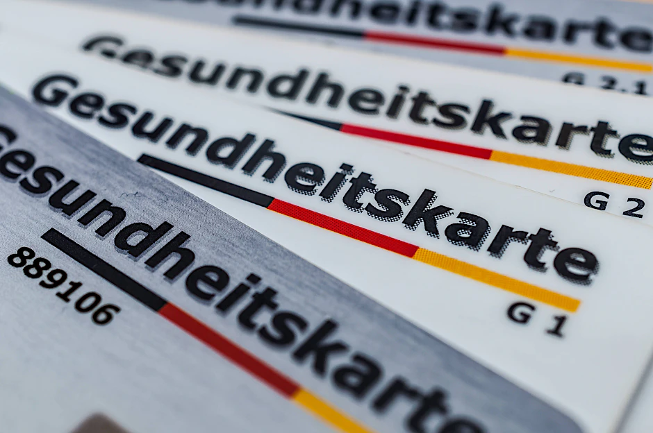 Gesundheitskarten liegen aufgefächert auf einem Tisch.