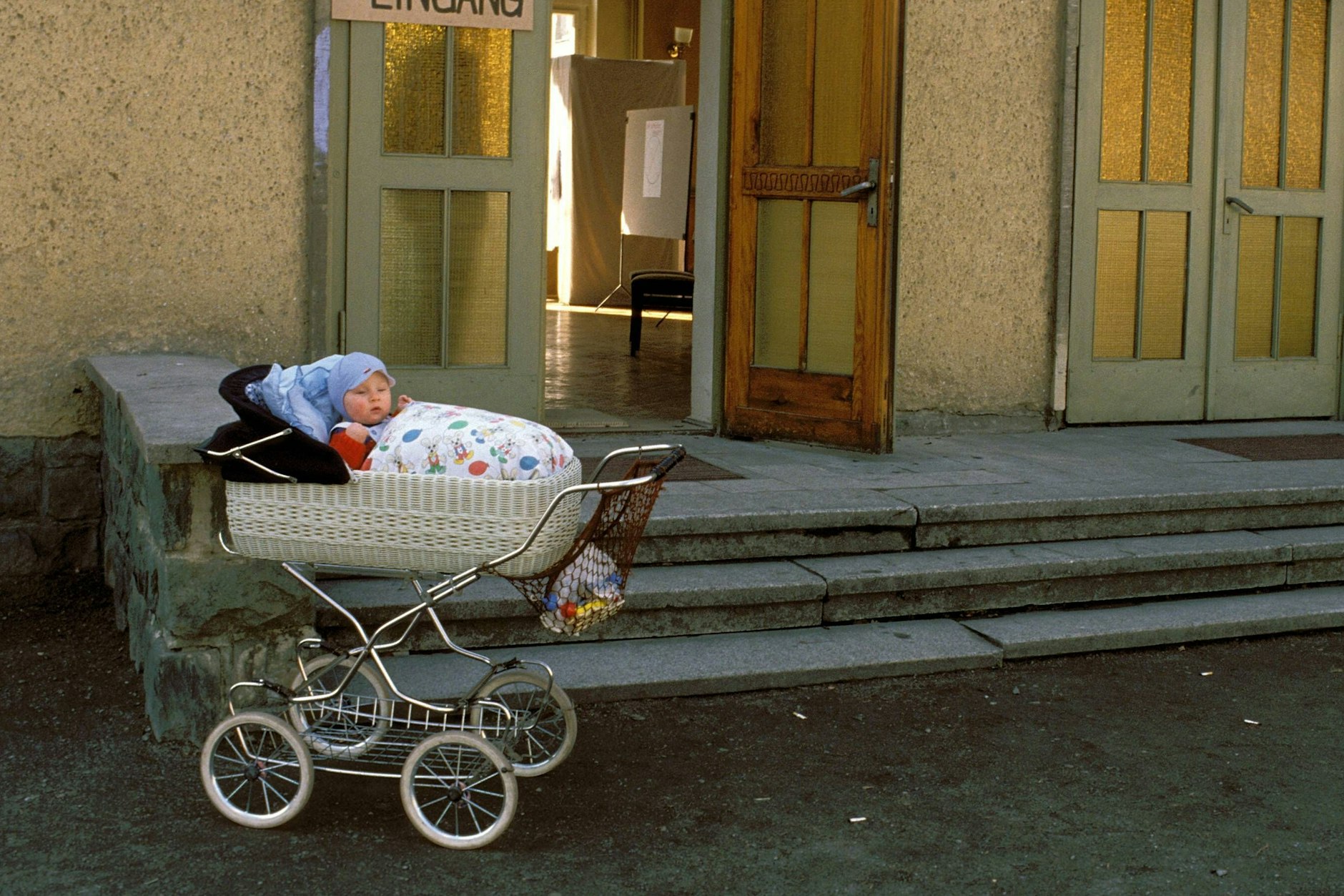 Die Eltern sind bei den ersten Wahlen in der DDR 1990 im Wahllokal. Das Kind haben sie im Kinderwagen draußen stehen lassen.