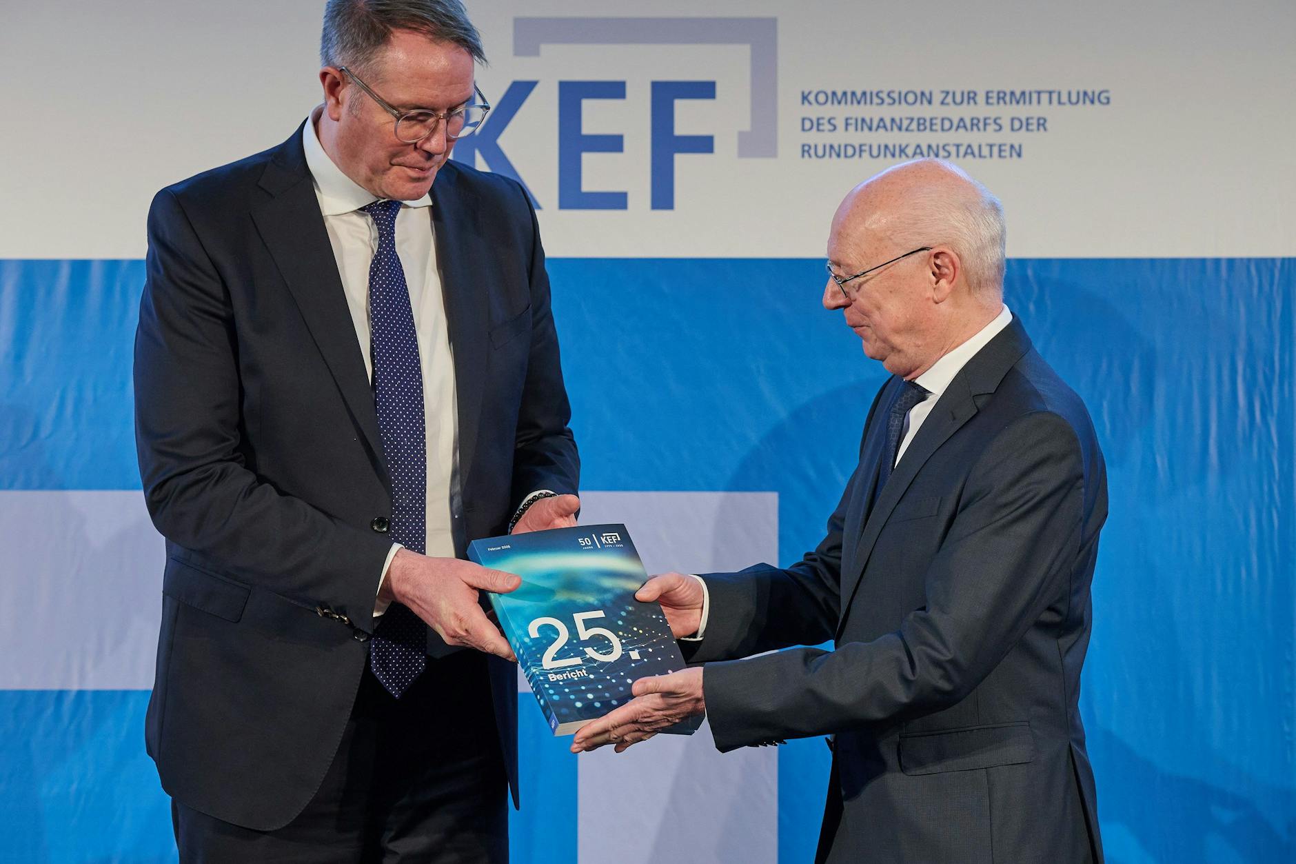 Martin Detzel (r.) von der KEF übergibt dem Vorsitzenden der Rundfunkkommission der Länder, Alexander Schweitzer, den Bericht der KEF.