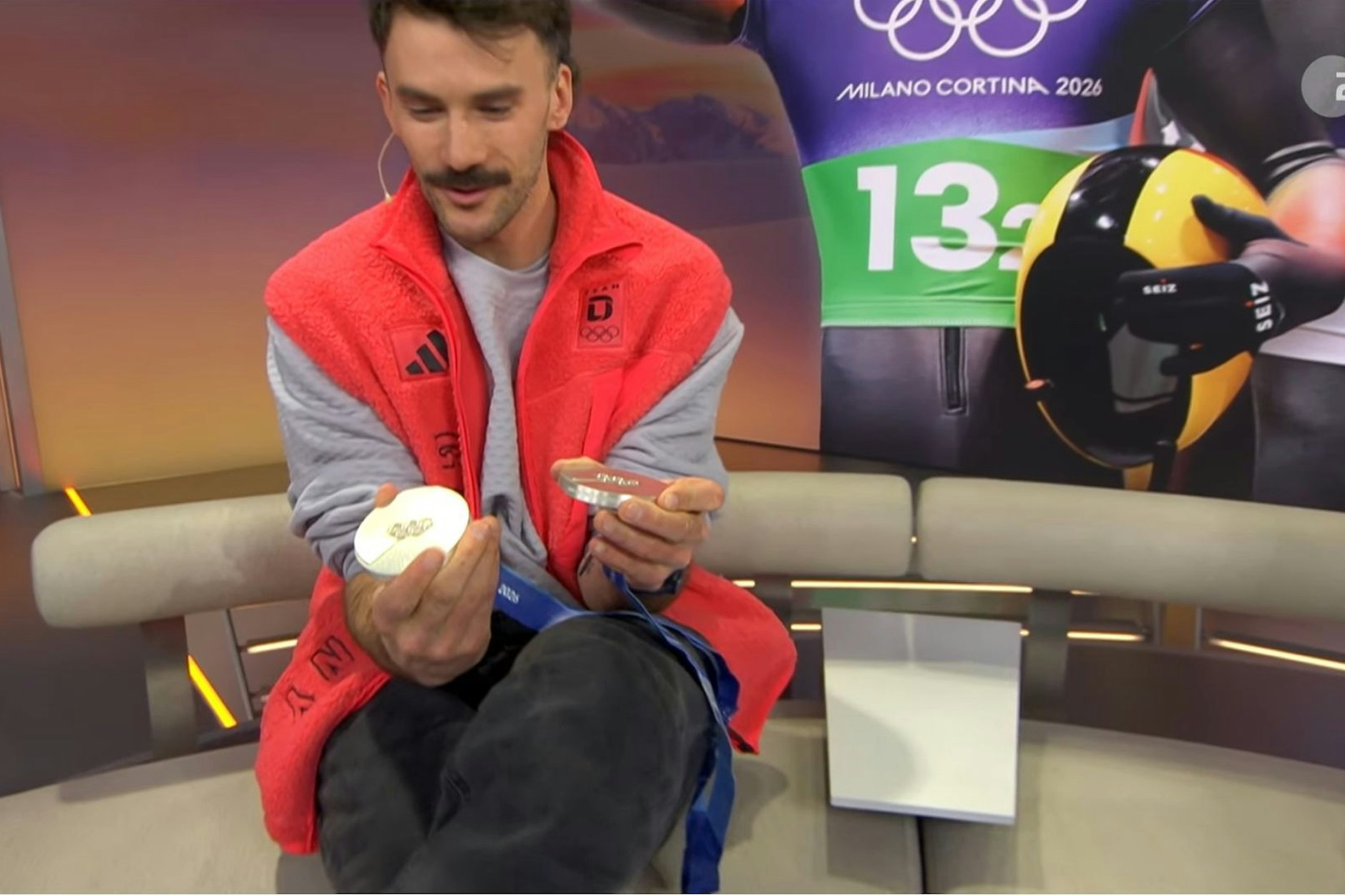 Skeletoni Axel Jungk zeigt seine beiden Silbermedaillen und stellt dabei Unregelmäßigkeiten fest.