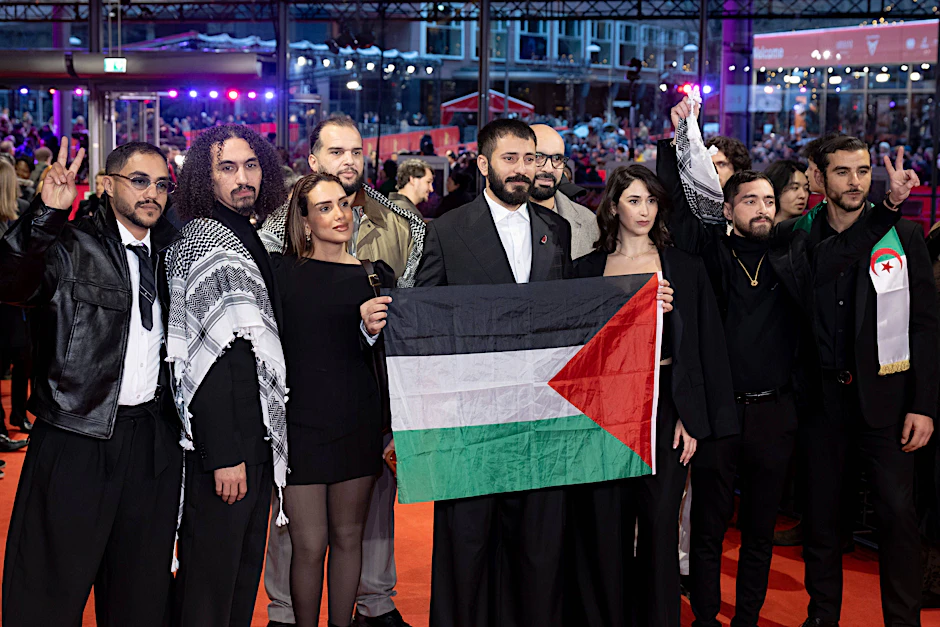 Schauspieler und Crew des Films „Chronicles From the Siege“ halten eine Palästina-Flagge auf dem Roten Teppich vor der Abschlussgala der 76. Berlinale.