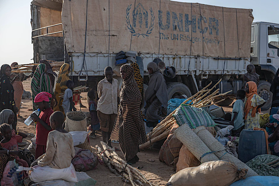 Sudanesische Flüchtlinge, die aus der Stadt Tine umgesiedelt wurden, tragen ihr Gepäck in der tschadischen Stadt Iridimi (2025).