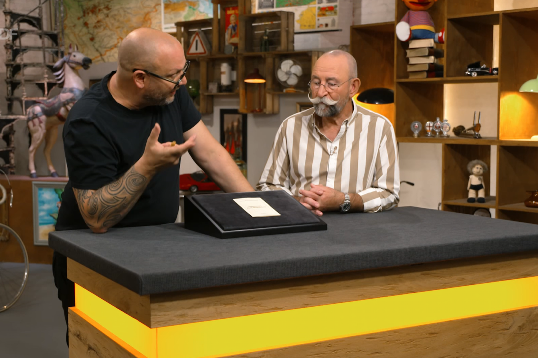 Ein Stück Papier aus der DDR bei der Expertise von „Bares für Rares“: Horst Lichter und Experte Sven Deutschmanek schauen sich die Identitätsbescheinigung aus Honeckers Zeiten an.