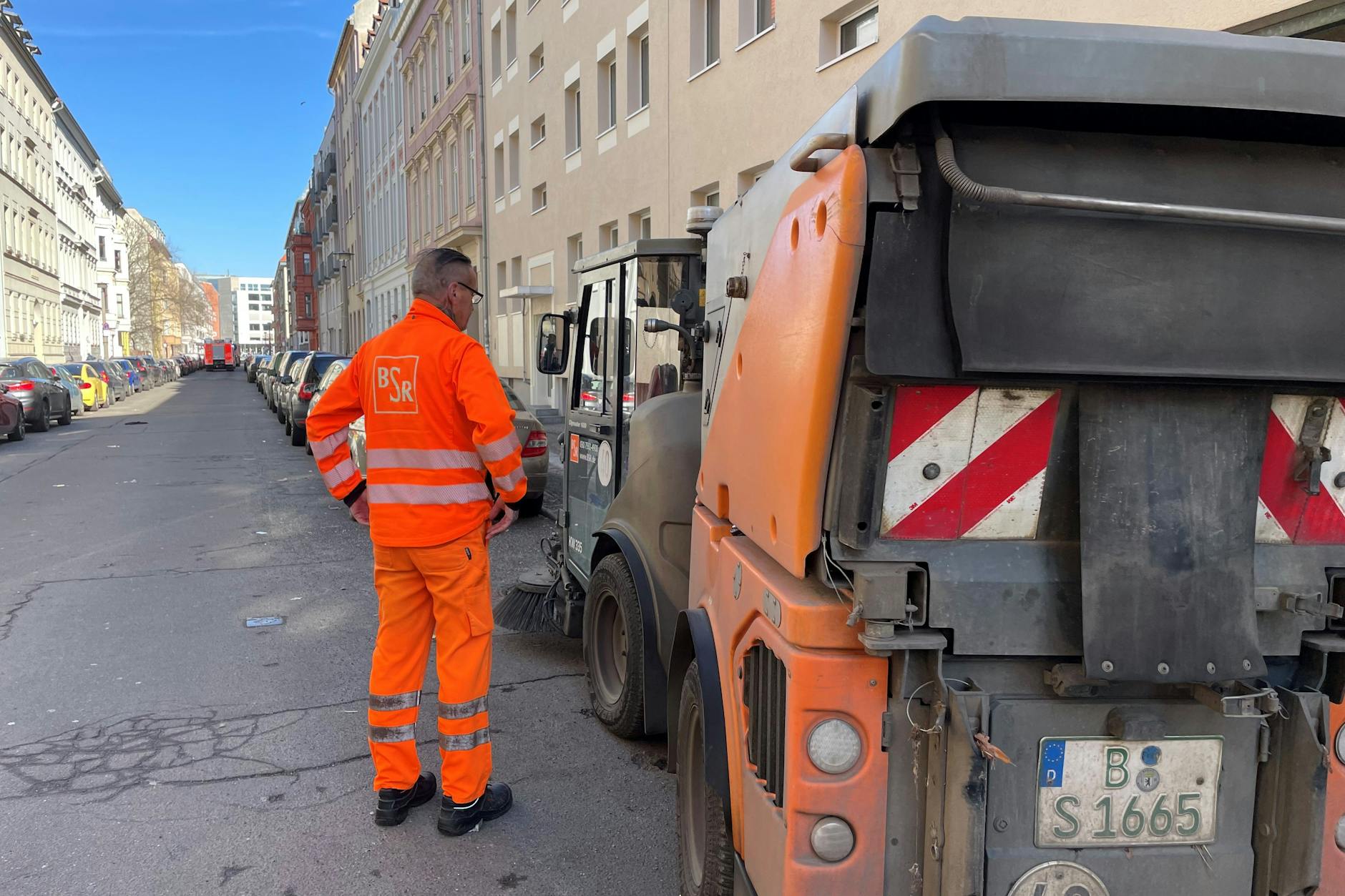 Der Fahrer der BSR-Kehrmaschine in der Almstadtstraße steht neben seinem Fahrzeug. Ihm ist zum Glück nichts passiert.