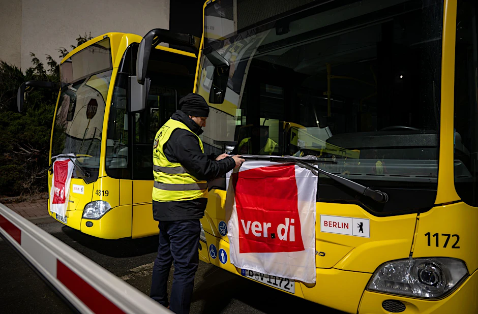 Straßenbahnfahrer Manuel von Stubenrauch befestigt während eines Warnstreiks bei der BVG eine Verdi-Fahne an einem Bus.