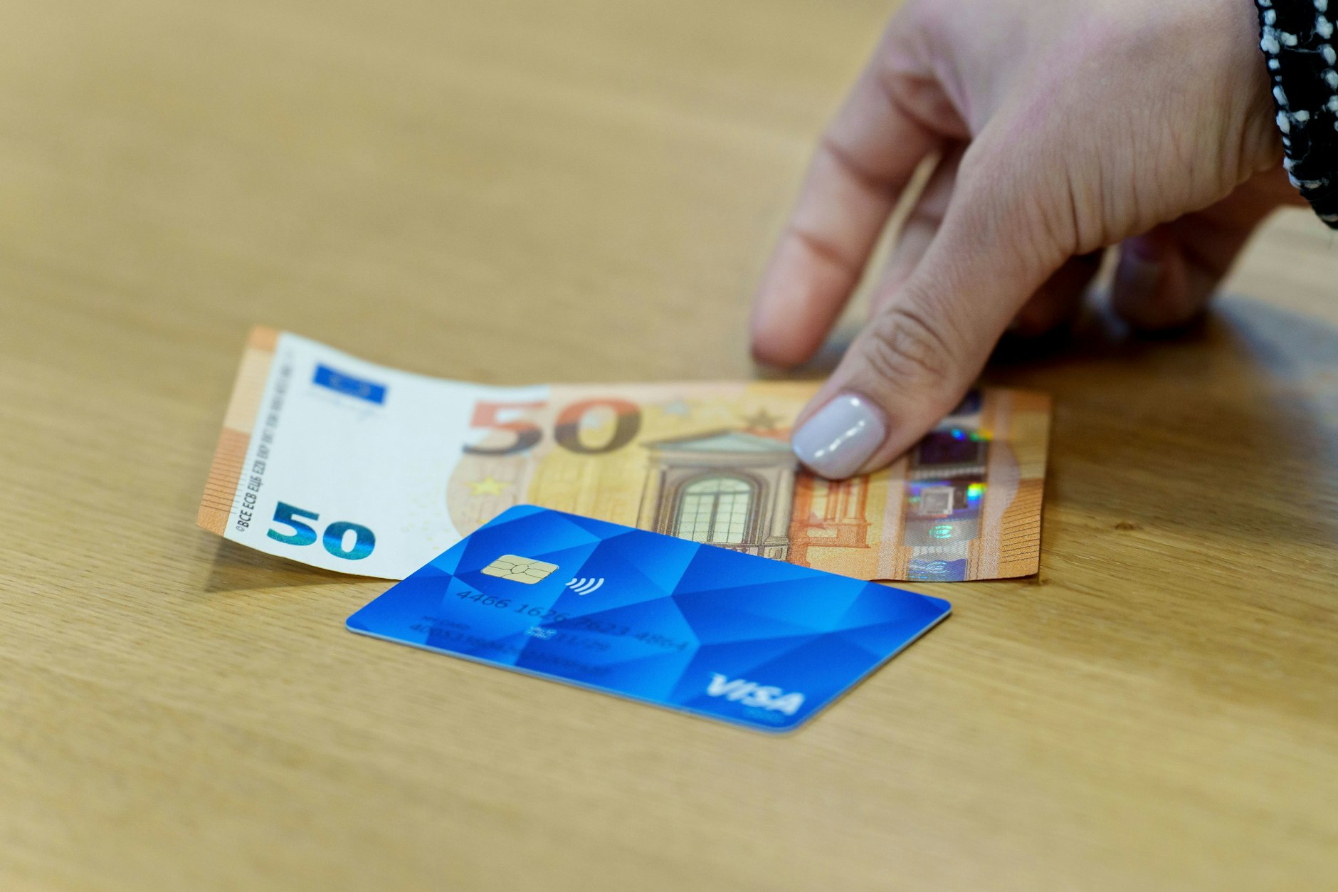 Eine Bezahlkarte für Asylbewerberinnen und Asylbewerber und ein 50-Euro-Schein liegen nebeneinander.