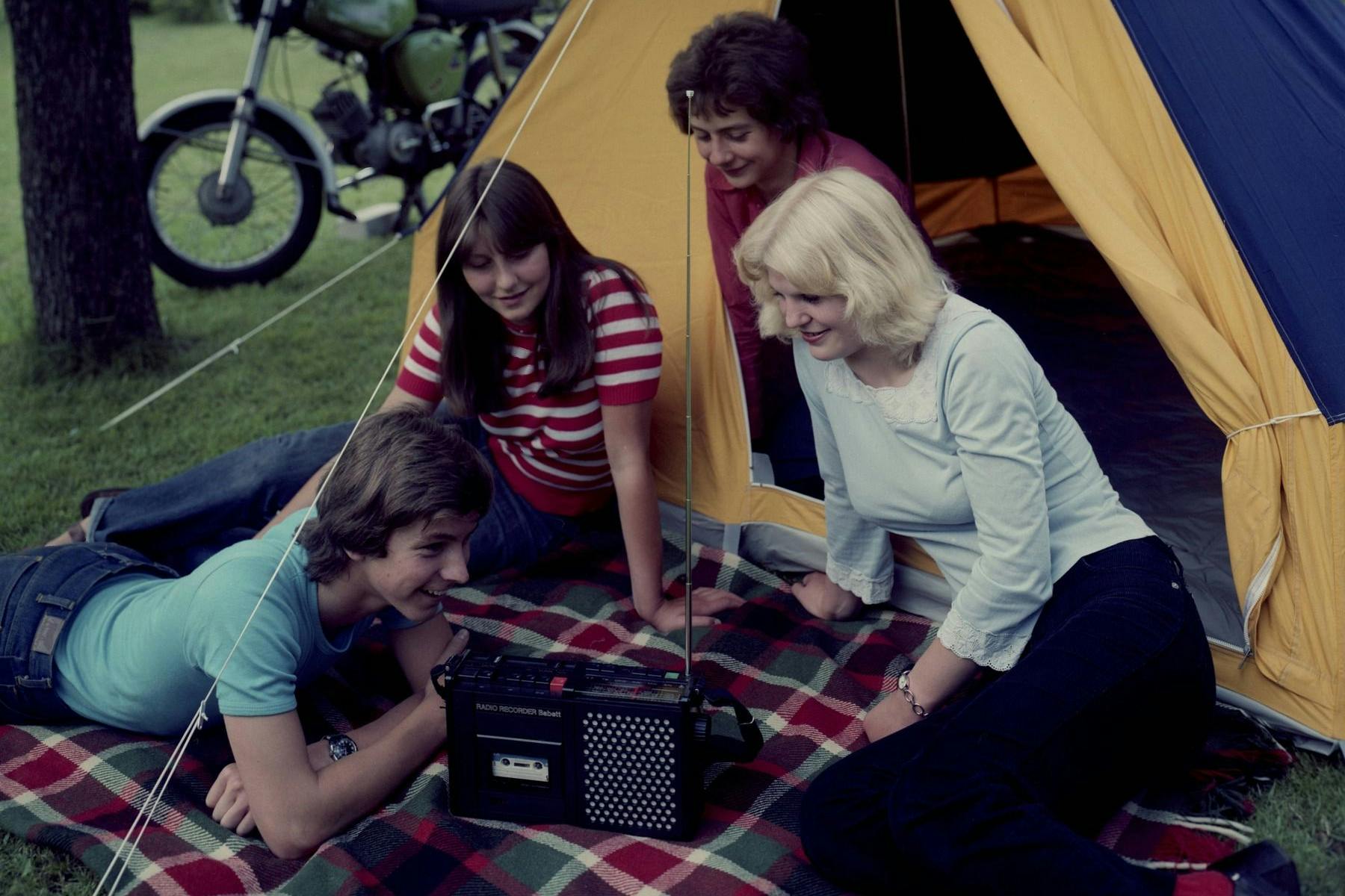 Jugendliche vor einem Zelt mit Musikrecorder. Mit dieser Werbeaufnahme wurde in der DDR für den Radiorecorder Babett KTR 430 aus dem VEB RFT Stern-Radio Berlin geworben.