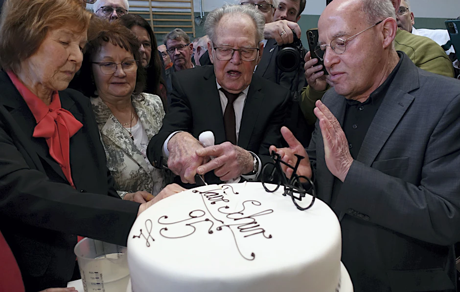 Täve Schur (2.v.r.) schneidet unter Applaus von Gregor Gysi (r.), Mitglied des Deutschen Bundestages, im Sportzentrum „Am Mühlberg“ in Kleinmühlingen eine dreistöckige Buttercreme-Torte mit einem Rennrad sowie der Aufschrift „Täve Schur 95“ an.