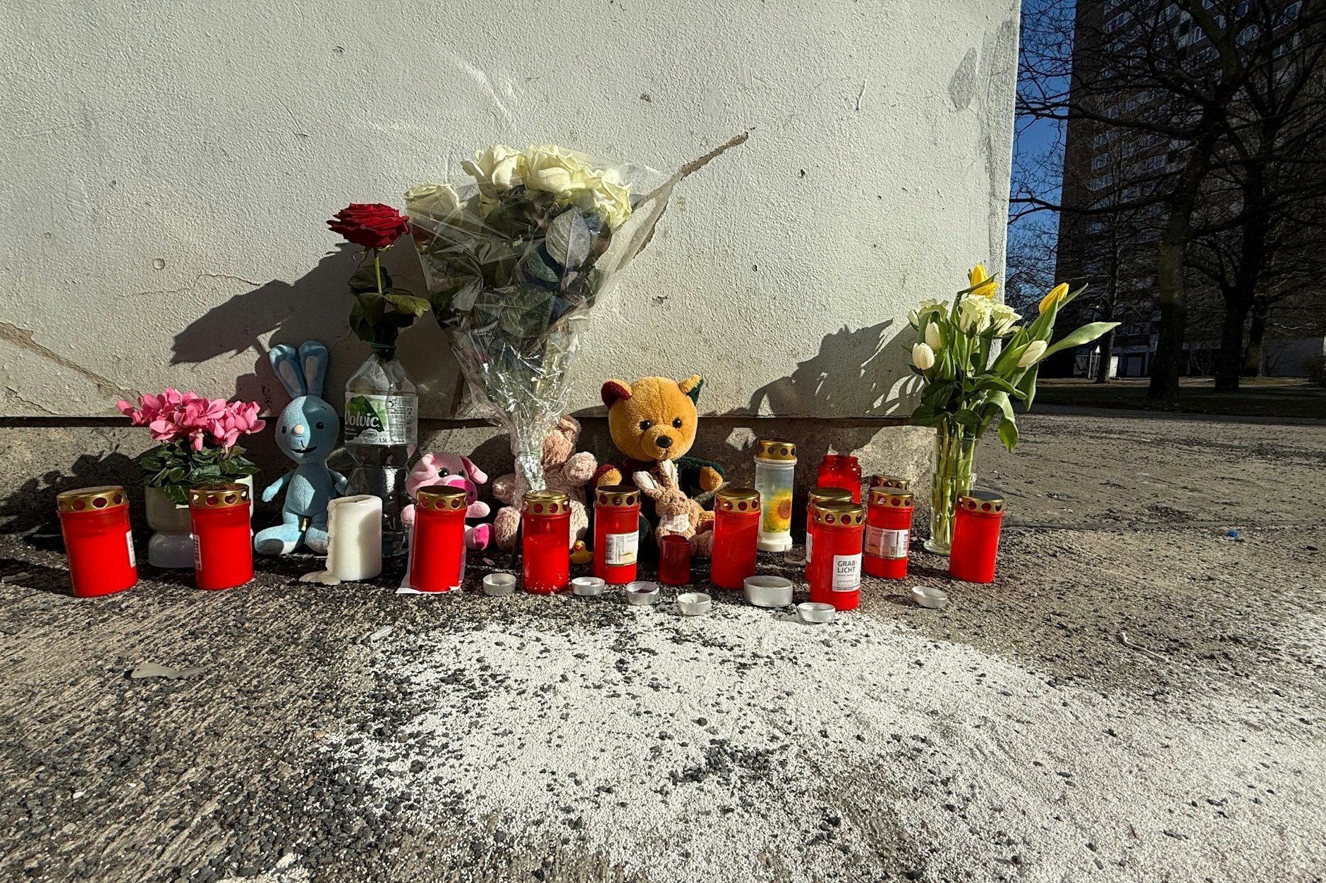 Blumen und Kerzen stehen an dem Hochhaus in Marzahn, aus dem ein vierjähriger Junge stürzte.