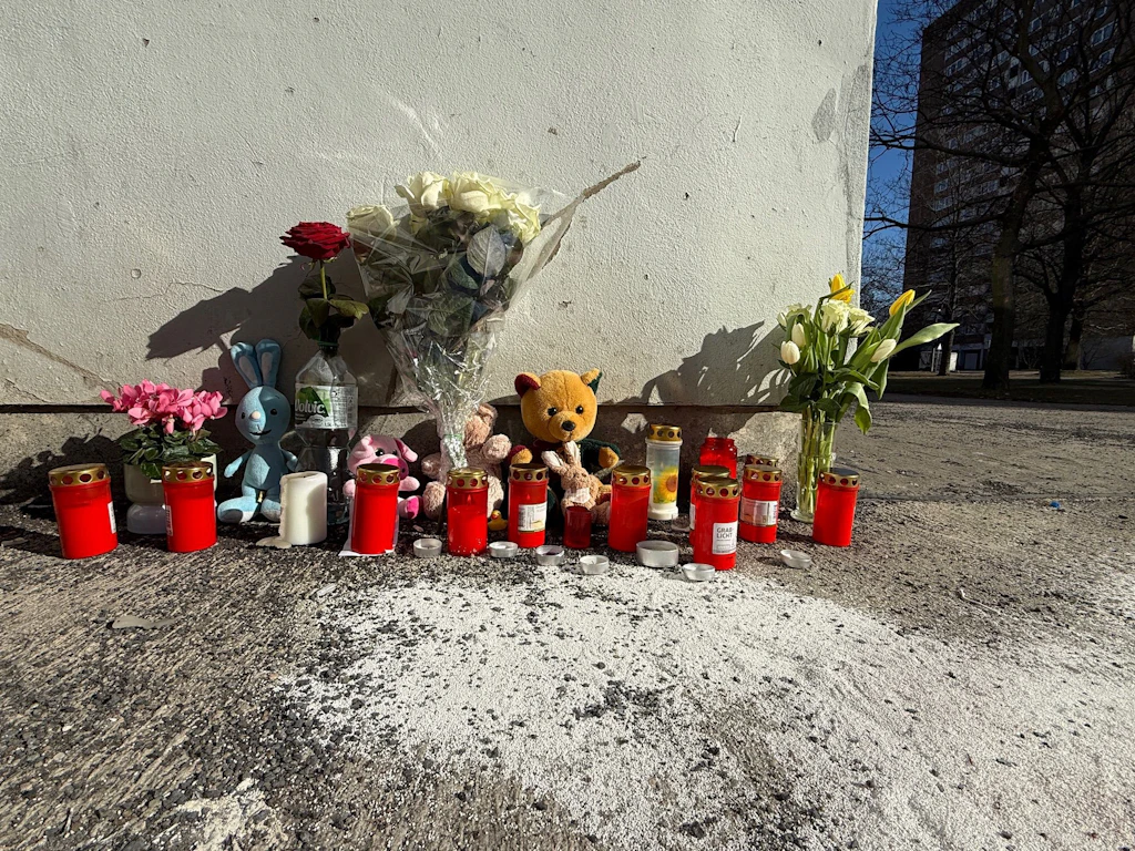 Blumen und Kerzen stehen an dem Hochhaus in Marzahn, aus dem ein vierjähriger Junge stürzte.
