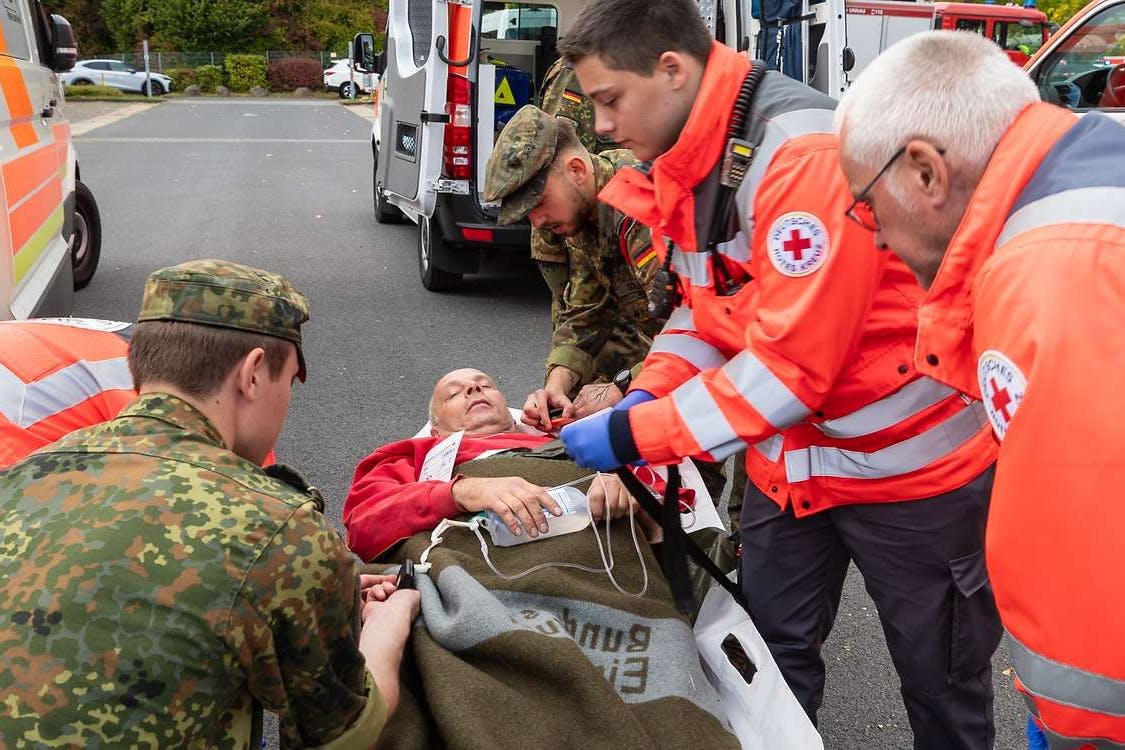 Bundeswehr-Sanitäter und zivile Rettungskräfte transportieren be einer Übung einen Verletzten ab.ve