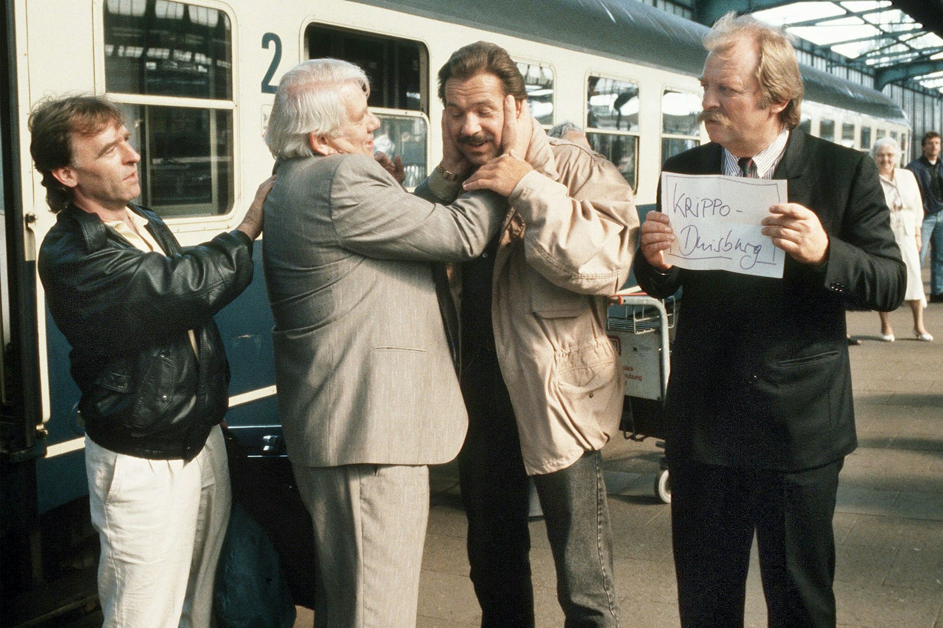 Die Folge „Unter Brüdern“ führte „Polizeiruf 110“ und „Tatort“ im Oktober 1990 zusammen. Thanner (Eberhard Feik, r.) und Schimanski (Götz George, 3.v.l.) nehmen die Kollegen Grawe ( Andreas Schmidt-Schaller, l.) und Fuchs (Peter Borgelt, 2.v.l.) aus Berlin-Ost am Duisburger Bahnhof in Empfang.