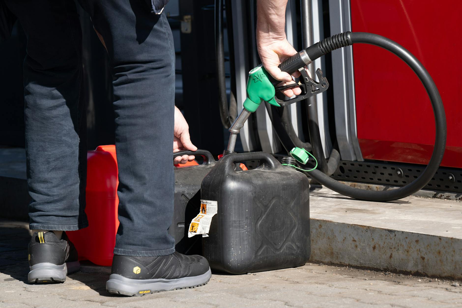 Ein deutscher Autofahrer füllt an einer Tankstelle in Tschechien günstigeres Benzin in Kanister.