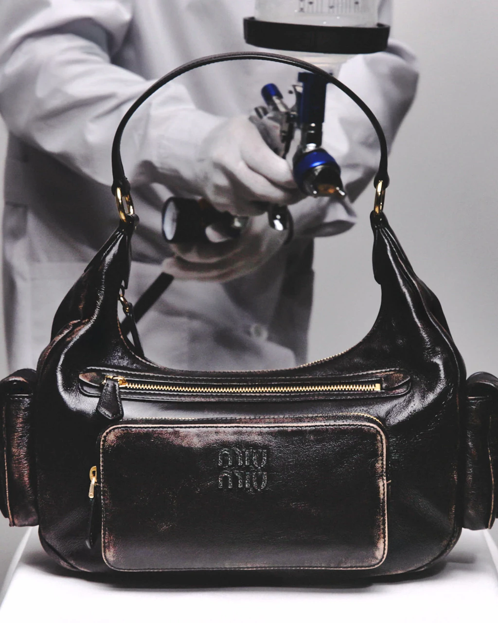 Was sonst Jahre dauert, wird hier künstlich inszeniert: Diese Miu-Miu-Handtasche bekommt den Patina-Look aufgesprüht.