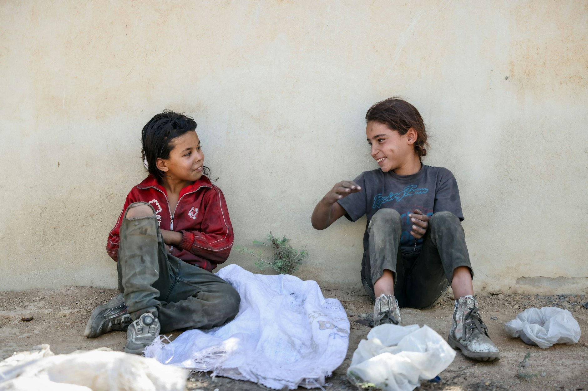 Nachdem sie im Müll nach verwertbaren Dingen gesucht haben, unterhalten sich zwei Kinder in Damaskus am Straßenrand.