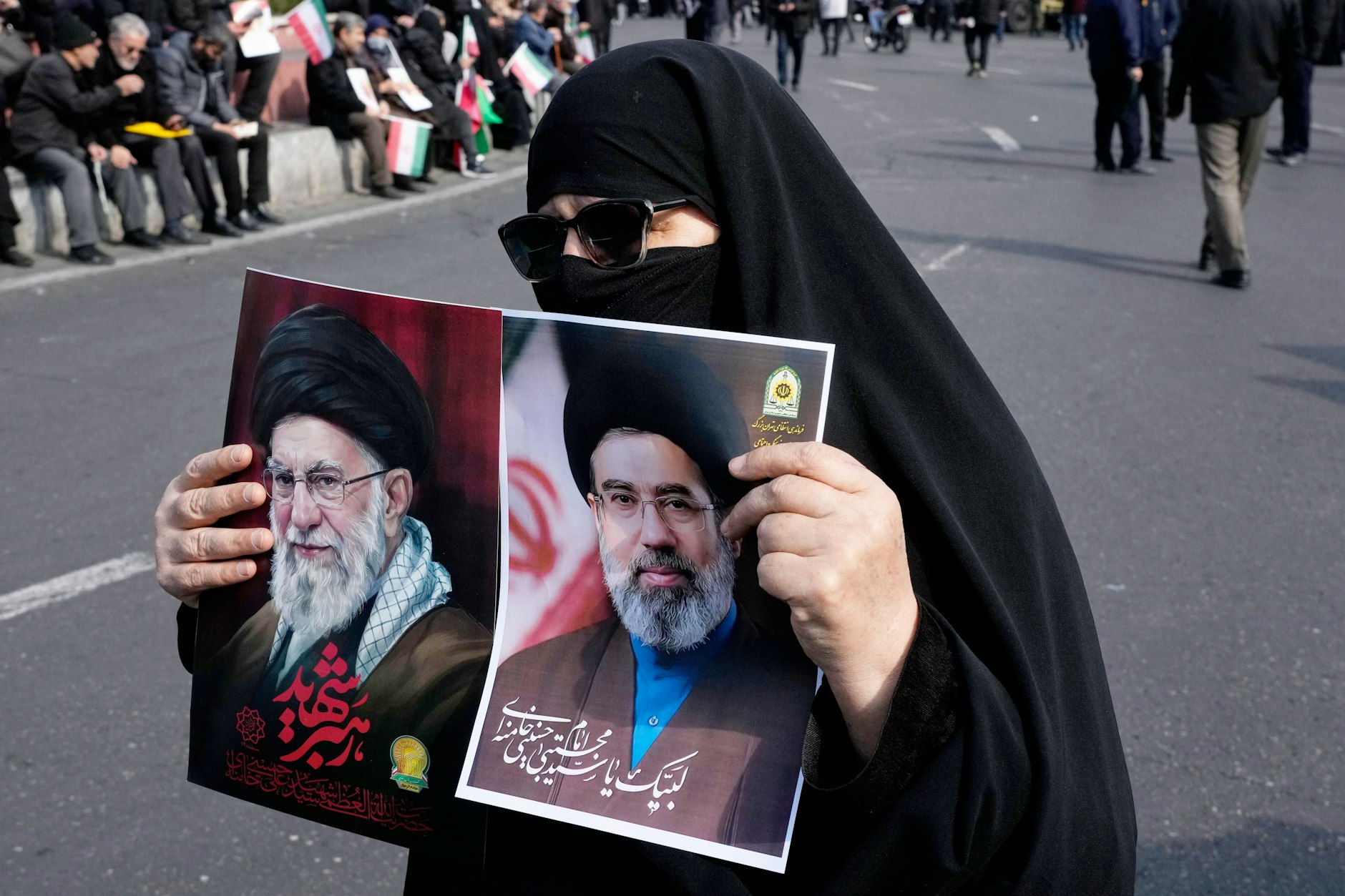 Eine Anhängerin der Islamischen Republik hält in Teheran Fotos des getöteten Obersten Führers Ali Chamenei und seines Sohnes und Nachfolgers Modschtaba&nbsp;Chamenei in die Höhe.