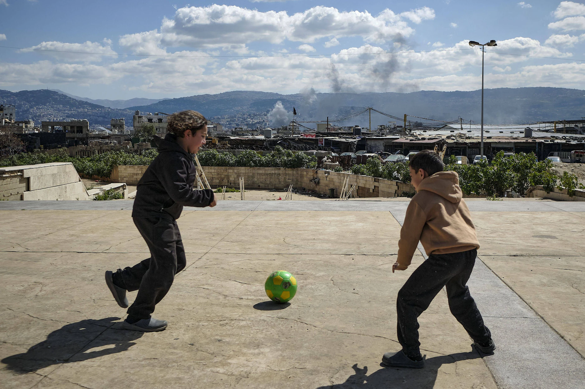 Zwei Kinder spielen in Beirut am Rande einer Notunterkunft Fußball.