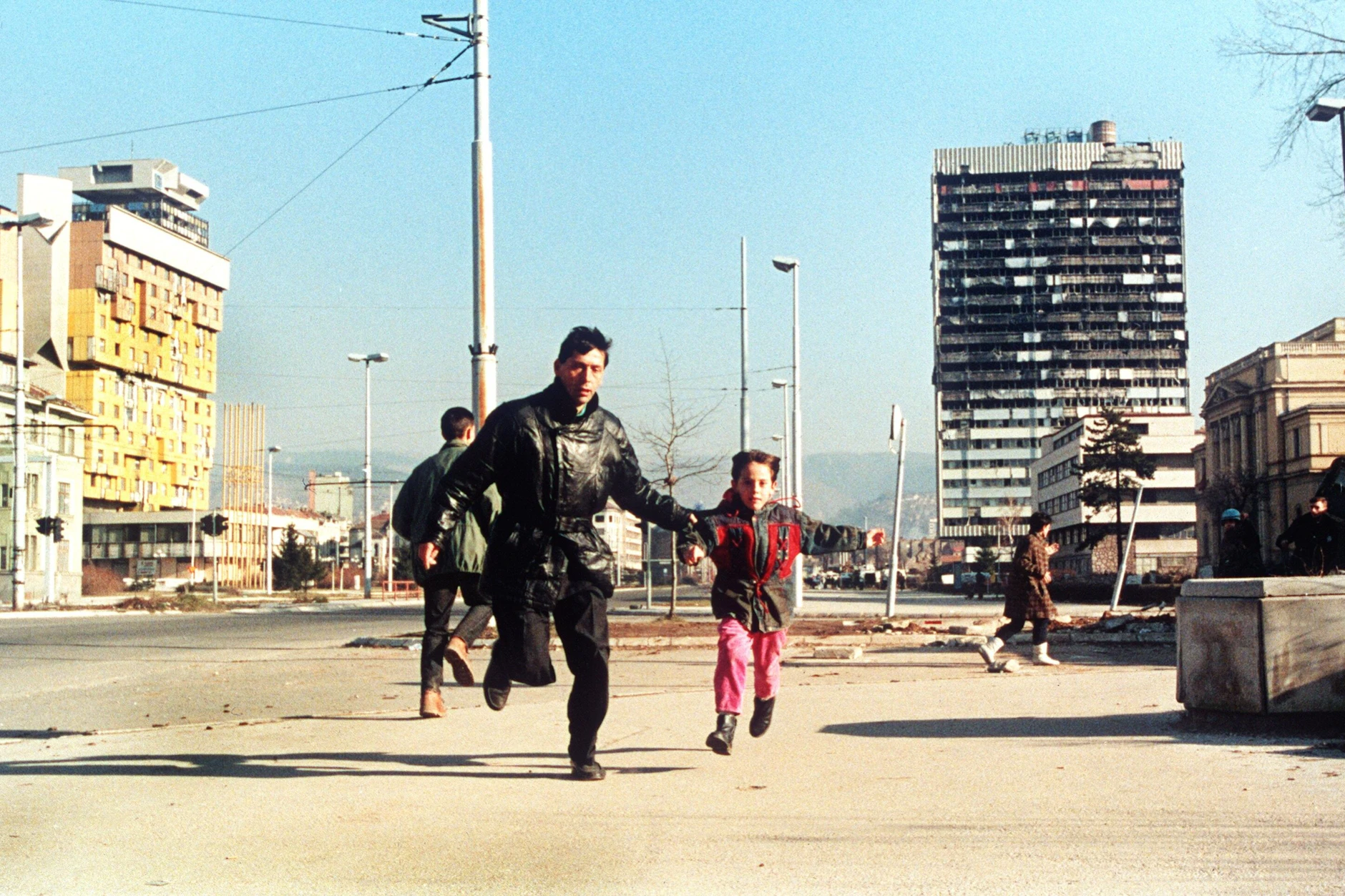 Ein Einwohner Sarajevos läuft im Dezember 1994 mit seinem kleinen Sohn an der Hand über die Straße, um sich in Sicherheit vor Heckenschützen zu bringen.