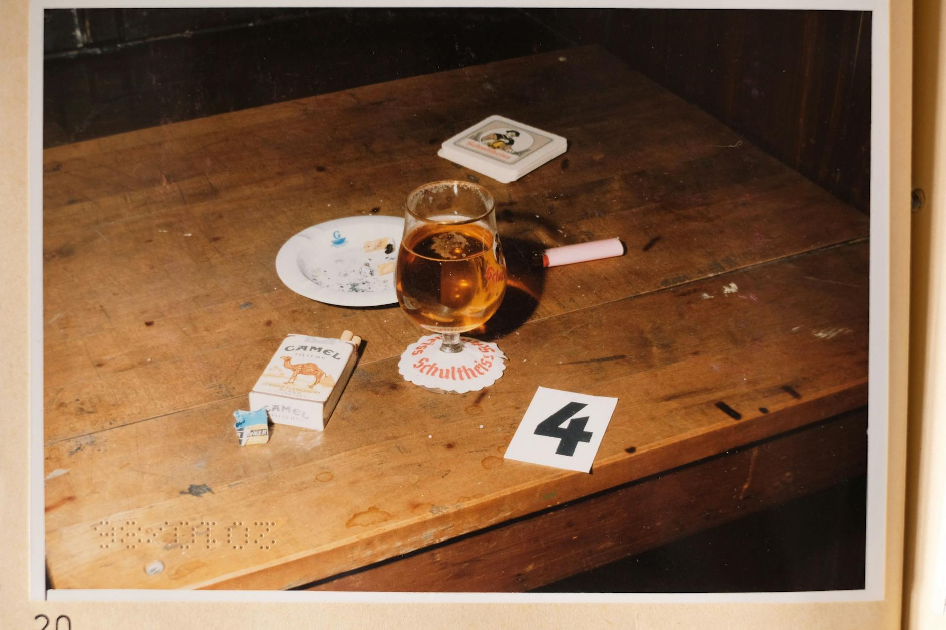 Das Polizei-Foto von 1986 aus der Kneipe: Auf dem kleinen Tisch liegt eine Schachtel Zigaretten neben einem noch vollen Glas Bier und einer Kippe im Aschenbecher.