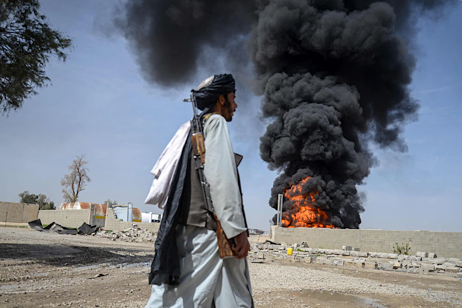 Ein Taliban-Sicherheitsmann nahe dem Flughafen von Kandahar. Im Hintergrund steigt Rauch nach pakistanischen Luftangriffen auf.