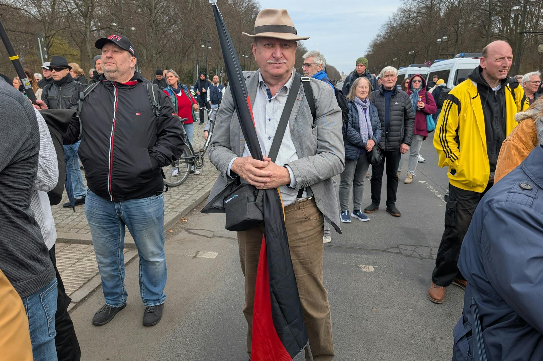 Bernd Pachal steht mit Hut und einer zusammengerollten Deutschlandfahne inmitten der Menschenmenge.