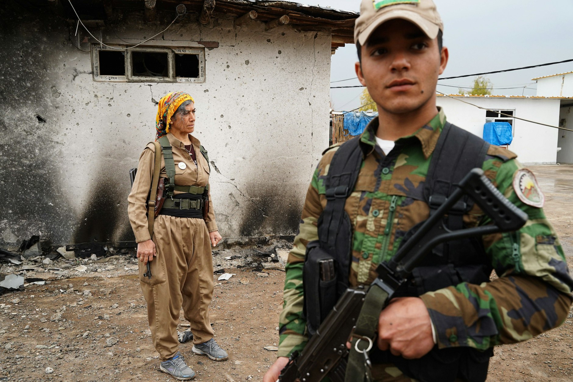 Kurdische Kämpfer vor beschädigtem Gebäude nach iranischem Drohnenangriff.