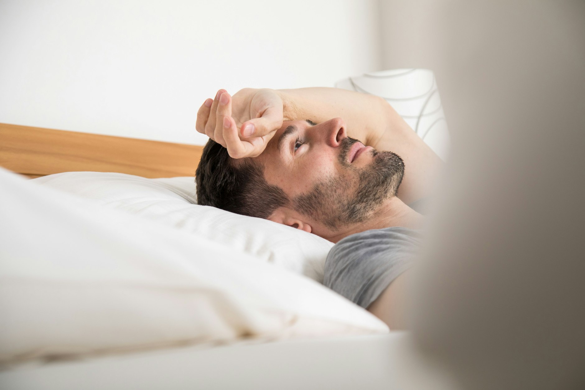 Ein Mann liegt erschöpft im Bett: Psychische Erkrankungen nehmen in Berlin zu.