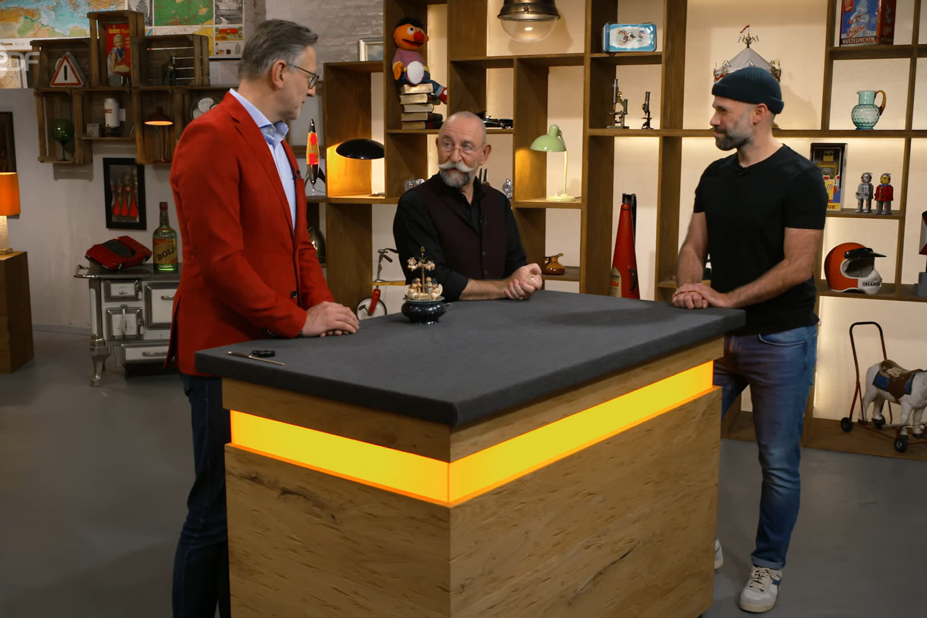 Experte Detlev Kümmel, Moderator Horst Lichter und Kandidat Rene Ruwe bei der Expertise bei „Bares für Rares“. Hier wird der Wert für die besondere Spieluhr aus der DDR ermittelt.