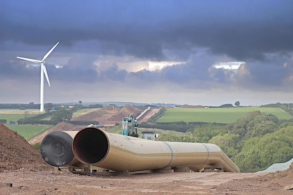 Verlegung einer Flüssiggas-Pipeline, im Hintergrund ein Windrad.