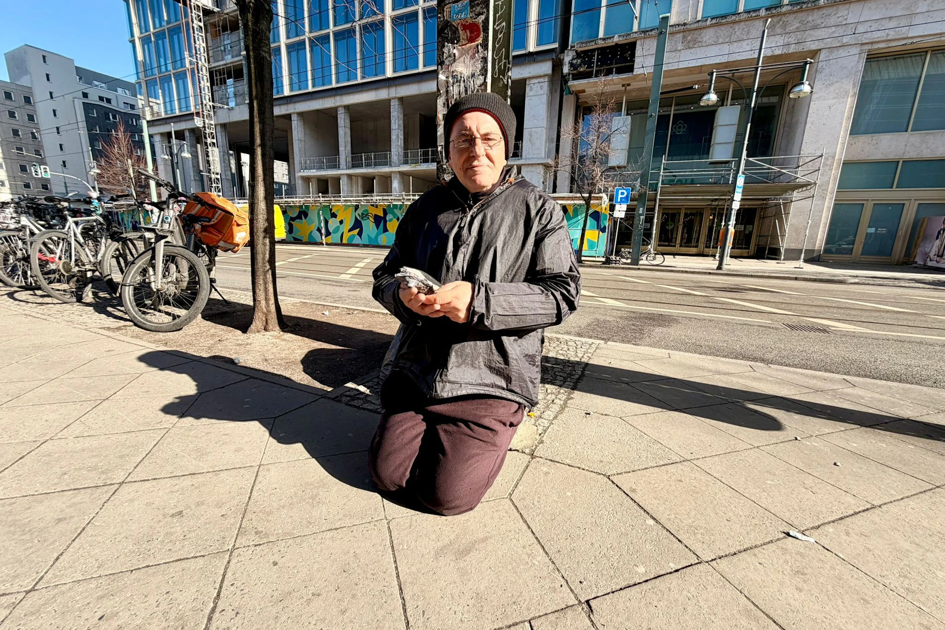Robert kniet am Alexanderplatz und bittet um Spenden.