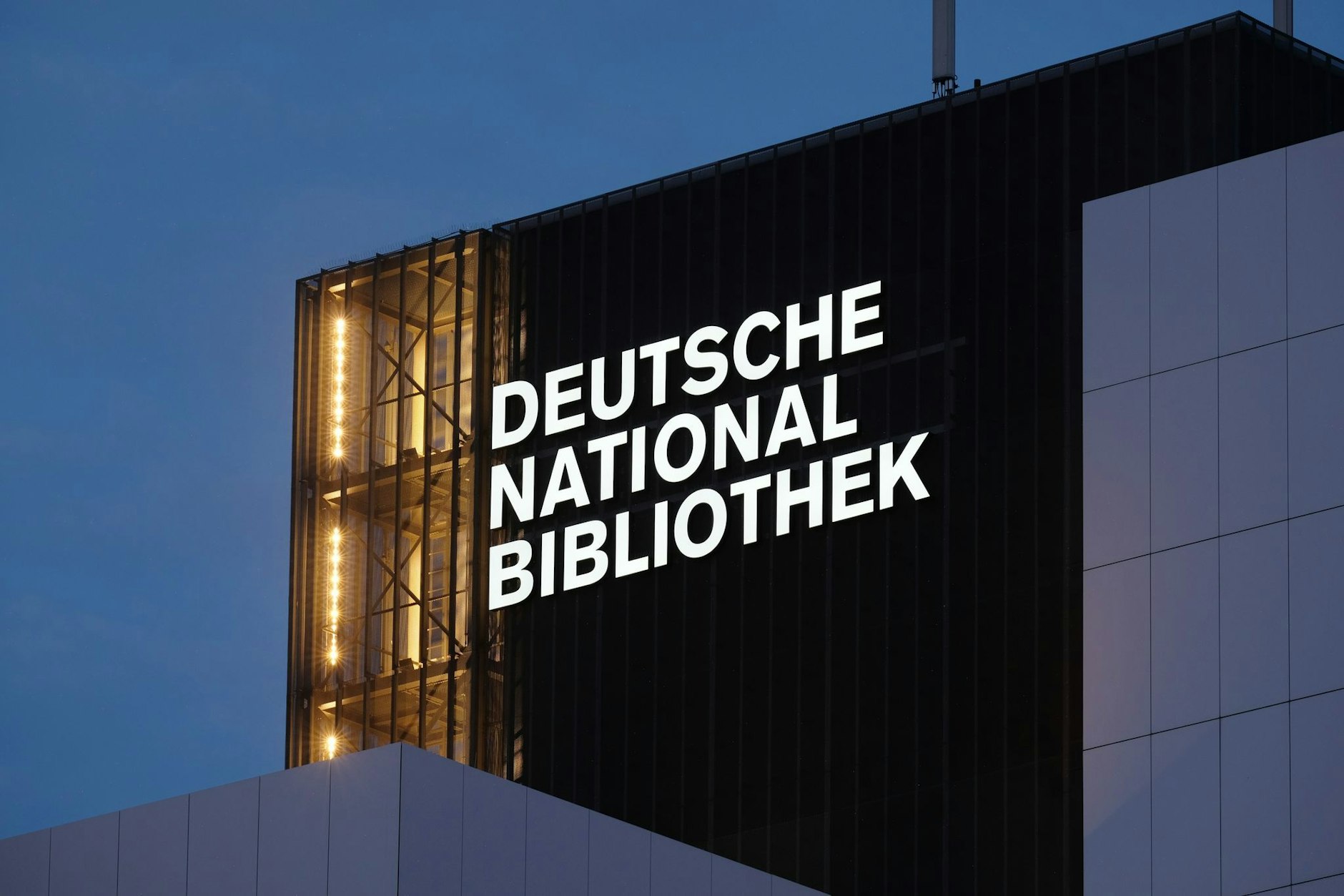 Der Schriftzug „Deutsche Nationalbibliothek“ (DNB) leuchtet an einem 55 Meter hohen Gebäude der früheren Deutschen Bücherei.