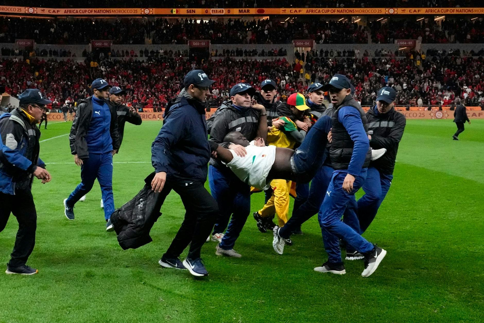 Sicherheitskräfte tragen einen Fan vom Platz.