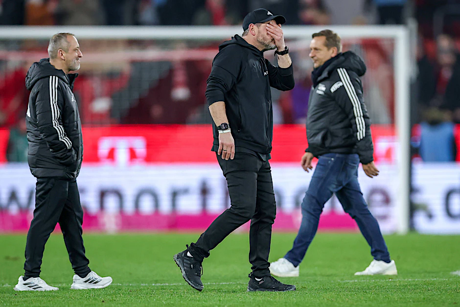 Steffen Baumgart (Mitte) ist anderer Meinung als Geschäftsführer Horst Heldt (r.) und sieht keiner Bevorzugung der Münchner entgegen.