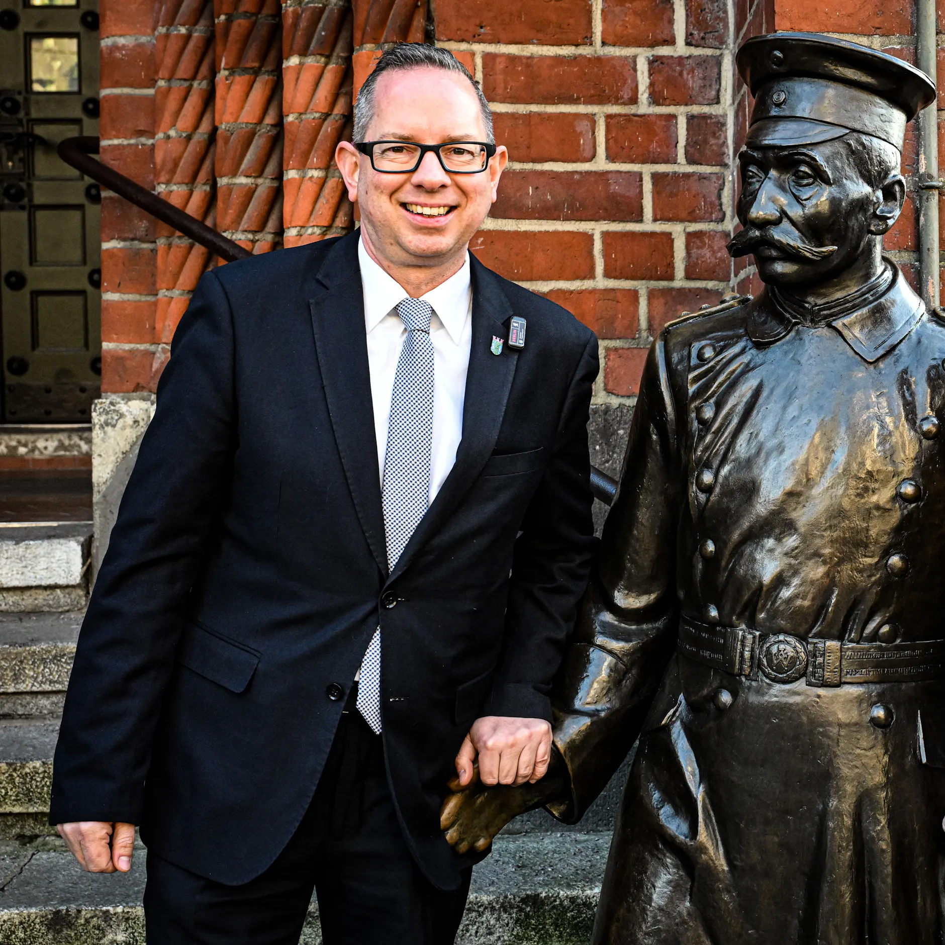 Bezirksbürgermeister Oliver Igel (SPD) am Denkmal des Hauptmannes von Köpenick, das vor dem Rathaus steht.