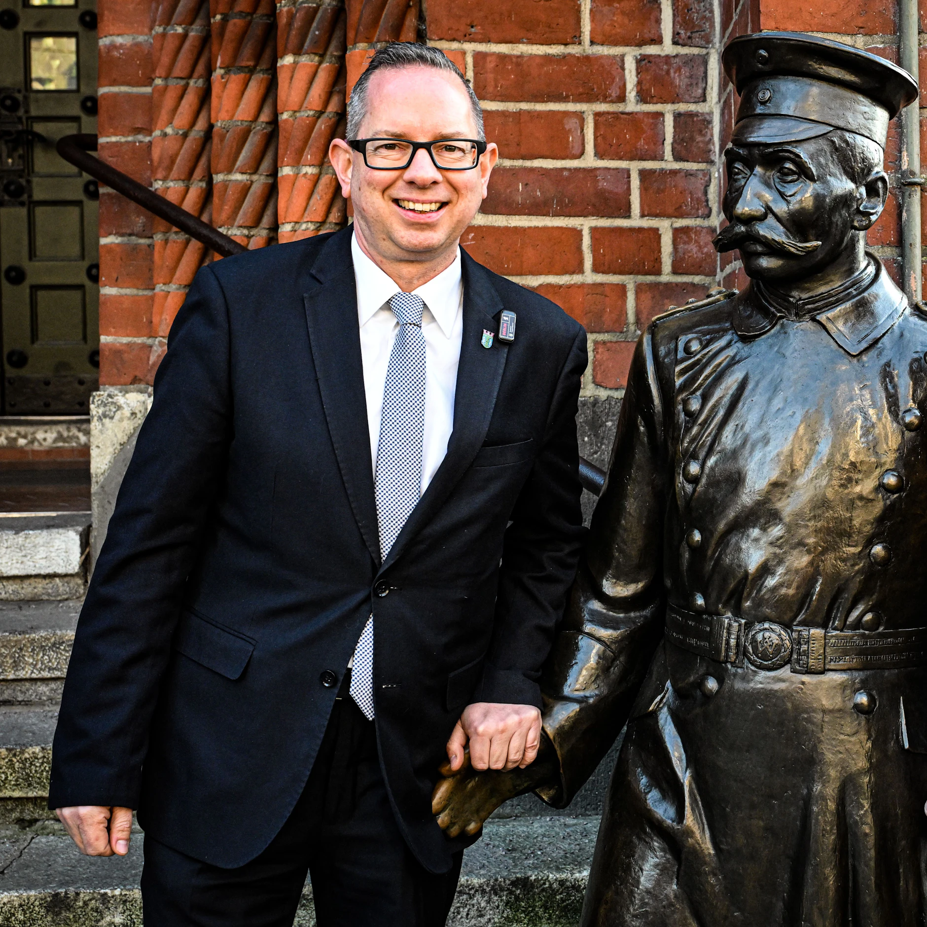 Bezirksbürgermeister Oliver Igel (SPD) am Denkmal des Hauptmannes von Köpenick, das vor dem Rathaus steht.