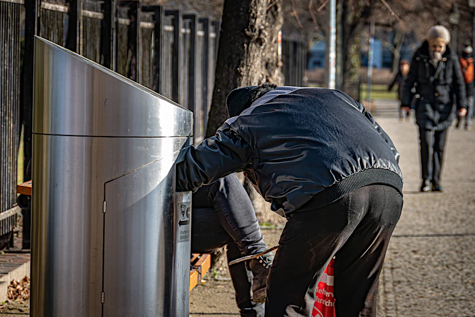 Ein Mann sucht in Potsdam in einem Mülleimer nach Pfandflaschen.