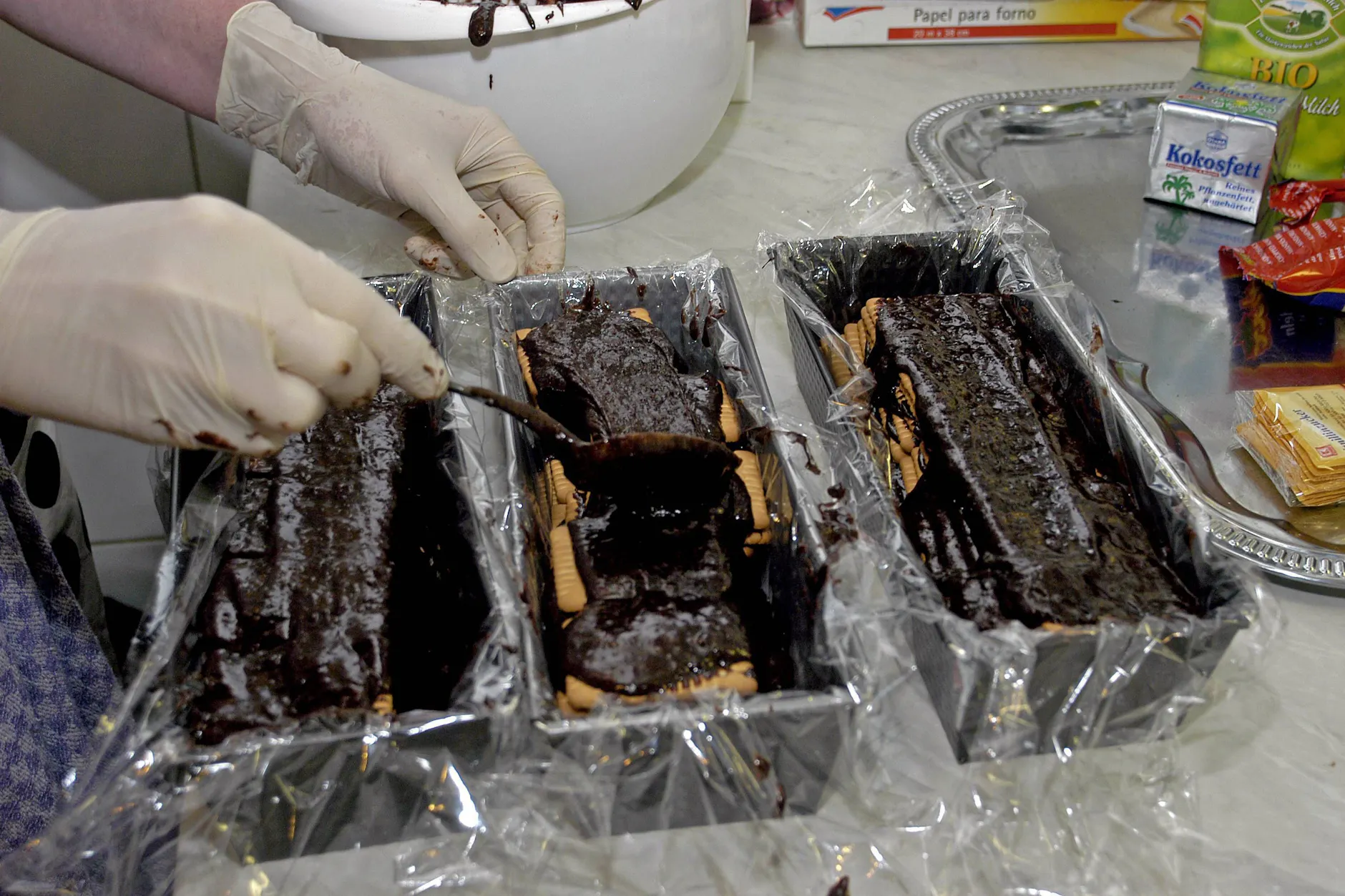 Die Kastenform wird mit Frischhaltefolie ausgelegt. Danach werden Kakaomasse und Kekese abwechselnd aufeinander geschichtet.