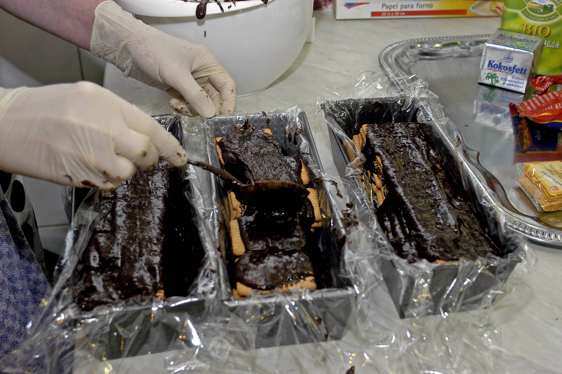 Die Kastenform wird mit Frischhaltefolie ausgelegt. Danach werden Kakaomasse und Kekese abwechselnd aufeinander geschichtet.