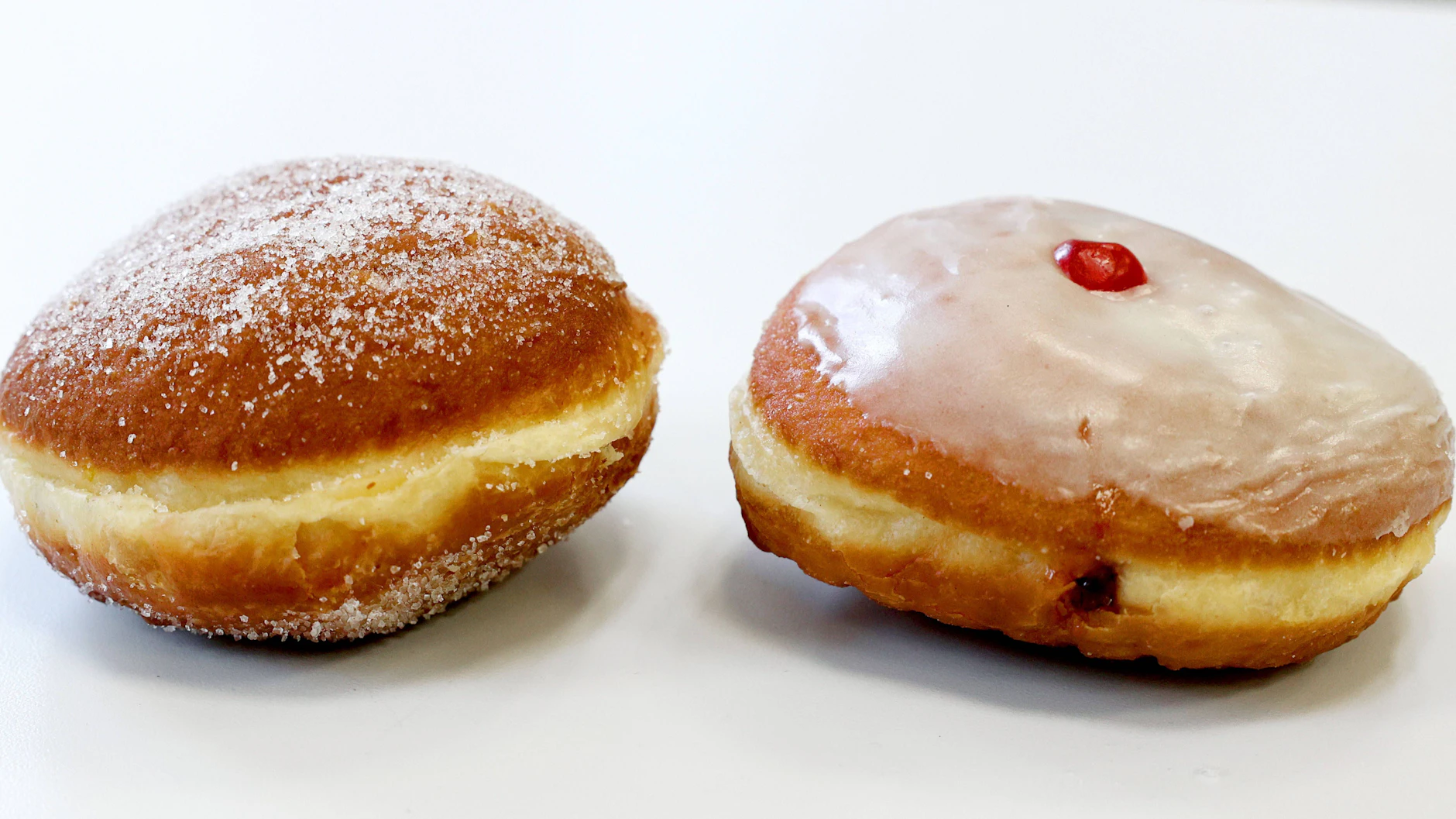 Diese beiden Varianten gibt es in Berlin: Pfannkuchen in Zucker gewälzt oder mit Zuckerguss. 